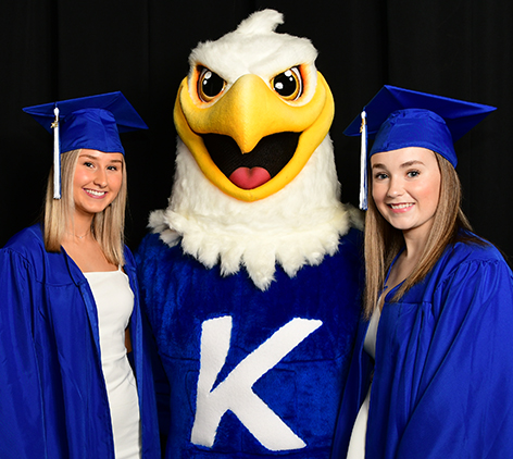 Sammy the mascot poses for a photo with two graduates